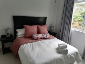 a bedroom with a large bed with pink pillows and a window at Caribbeans Estates Villa T13 Tortuga in Port Edward