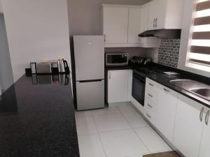 a kitchen with white cabinets and a white refrigerator at Caribbeans Estates Villa T13 Tortuga in Port Edward