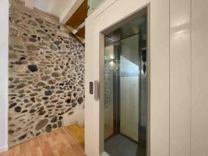 a bathroom with a stone wall and a walk in shower at NEW! Renovated house with terrace in Cambrils in Cambrils