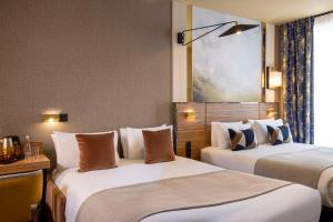 Una habitación de hotel con dos camas y una ventana. en Hotel Le Rocroy, en París