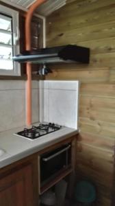 a kitchen with a stove in a tiny house at Studio Griyav- dans villa les Polycias in Sainte-Luce