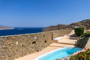 a stone retaining wall with a swimming pool and a stairway at Villa Isabella Family villa close to the beach in Mýkonos City