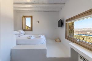two beds in a white room with a window at Villa Isabella Family villa close to the beach in Mýkonos City