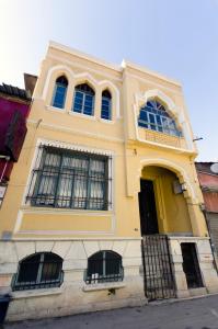 un edificio amarillo con 4 ventanas en una calle en Mansion with Lemon Tree en İzmir
