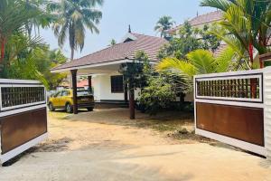 uma casa com dois portões de madeira em frente em KARIYIL KAYALORAM HOMESTAY em Shertallai