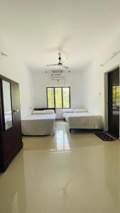 Cette chambre blanche dispose de deux lits et d'un plafond. dans l'établissement KARIYIL KAYALORAM HOMESTAY, à Shertallai