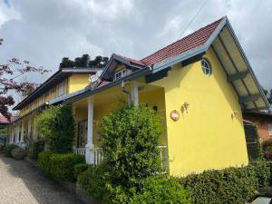 une maison jaune avec un toit rouge dans l'établissement Apartamentos Sulla Collina Centro de Gramado localizado próximo da rua Coberta, à Gramado