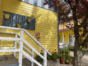 une maison jaune avec un escalier et une fenêtre dans l'établissement Apartamentos Sulla Collina Centro de Gramado localizado próximo da rua Coberta, à Gramado