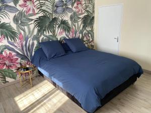 1 dormitorio con cama azul y papel pintado tropical en La Cayenne en Salazie