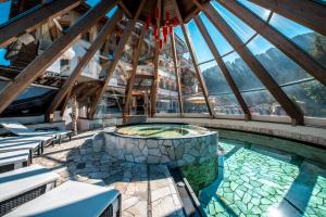 een binnenzwembad in een gebouw met een glazen plafond bij Renè Dolomites Boutique Hotel in Pozza di Fassa