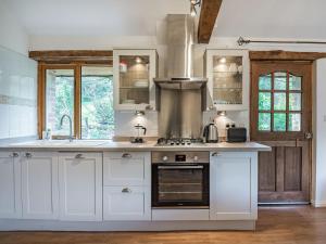 cocina con armarios blancos y fogones en Maple Tree Cottage, en Branscombe