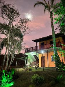 uma casa à noite com uma palmeira em Pousada Chalés dos Montes em Santana dos Montes
