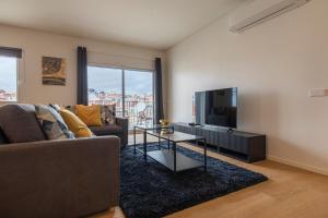 ein Wohnzimmer mit einem Sofa und einem Flachbild-TV in der Unterkunft Saldanha Flats I by Innkeeper in Lissabon