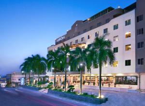 a building with palm trees in front of a street at ASTON Karimun City Hotel in Tanjung Balai Karimun