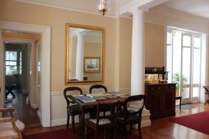 una sala da pranzo con tavolo, sedie e uno specchio di Tintagel Guest House a Città del Capo