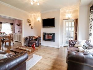 a living room with leather furniture and a tv at Nantclwyd in Llangollen