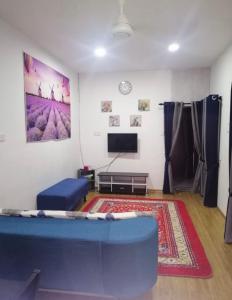 a living room with a blue couch and a tv at Sobey Laris Homestay RAZLEEN in Ketereh