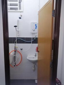 a bathroom with a sink and a hose at Sobey Laris Homestay RAZLEEN in Ketereh