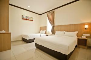 a hotel room with two beds and a window at Hotel Setia in Kluang