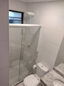 uma casa de banho branca com um chuveiro e um WC. em Itacimirim - Duplex Aconchegante, Pé na Areia em Itacimirim