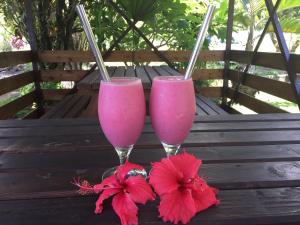 two glasses of pink drinks sitting on a wooden bench at Fare To'erau & Mara'amu in Papetoai