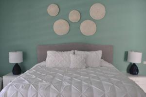 1 dormitorio con 1 cama blanca con 3 platos en la pared en Condo/ Depa - Marea Azul - Playa del Carmen en Playa del Carmen