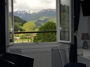 a room with a window with a view of mountains at Logis Hôtel Restaurant SPA le Beau Site in Chambon-sur-Lac