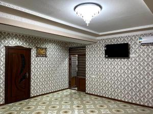 a living room with a television and a door at Hotel Mohina in Samarkand