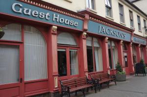 a red building with benches in front of a store at Jacksons Restaurant and Accommodation in Roscommon