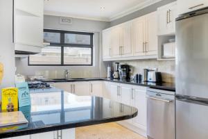 een keuken met witte kasten en een glazen aanrecht bij Backup Powered Atlantic Sea-View Penthouse in Kaapstad