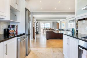 een keuken met een koelkast en een woonkamer bij Backup Powered Atlantic Sea-View Penthouse in Kaapstad