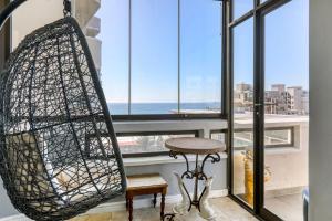 een schommel voor een raam met uitzicht op de oceaan bij Backup Powered Atlantic Sea-View Penthouse in Kaapstad