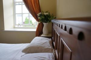 Jacksons Restaurant and Accommodation في روسكومون: غرفة نوم بسرير ونافذة بها نبات