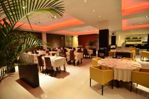 a restaurant with white tables and chairs and a plant at Amérian Villa Maria Park Hotel in Villa María