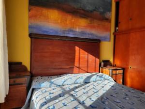 1 dormitorio con 1 cama y una pintura en la pared en Casa Amarrilla en San Clemente del Tuyú
