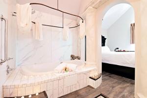 a white bathroom with a tub and a bed at Chateau Avalon in Kansas City