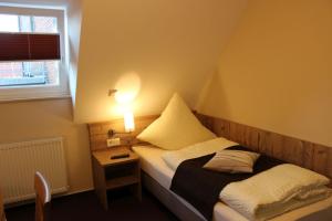 ein kleines Schlafzimmer mit einem Bett und einem Nachttisch in der Unterkunft Gasthof Klosterkeller in Kronach