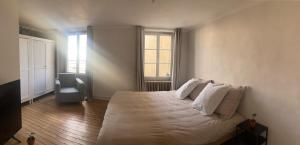 a bedroom with a bed with white sheets and pillows at Appartement cosy face à la Mayenne in Laval