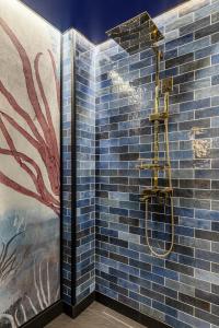 baño con ducha y pared de azulejos azules en HOLT - Jules Verne's Imaginarium, en Bucarest