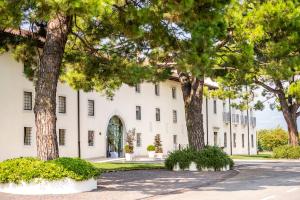 biały budynek z drzewami przed nim w obiekcie Hotel Villa I Pini w mieście Malo
