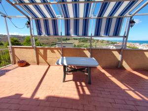 a bench on a patio with a blue and white umbrella at B&B Le Tre Palme in Ancona