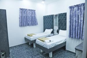2 camas individuales en una habitación con cortinas azules en JSM Residency en Chennai