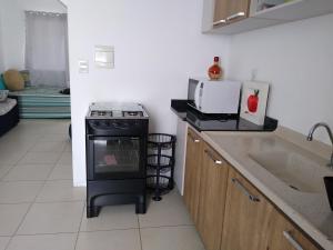 a kitchen with a stove and a microwave and a sink at Solar Bella Torres in Passo de Torres