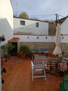 a patio with two chairs and a table and an umbrella at Acogedora casa de pueblo con piscina in Fuenteheridos