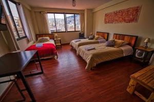 拉巴斯的住宿－ISKAY BOUTIQUE HOSTEL，客房设有两张床、一张桌子和一张书桌。