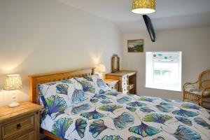 a bedroom with a bed with a blue and white comforter at Cronk Darragh Cottage in Castletown