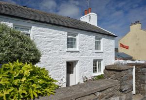 Cabaña de piedra blanca con puerta blanca y ventana en Cronk Darragh Cottage, en Castletown