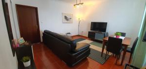 a living room with a leather couch and a table at Casa do Lado, Flores Açores in Lajes das Flores