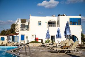 a white building with chairs and a swimming pool at Blue Beach Villas Apartments in Stavros