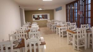 a dining room with white chairs and tables and windows at Hotel Monterrey in Termas de Río Hondo